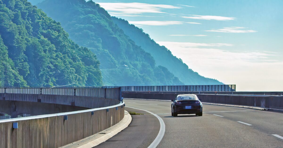 山沿いのカーブした道路を走る黒いスポーツカー