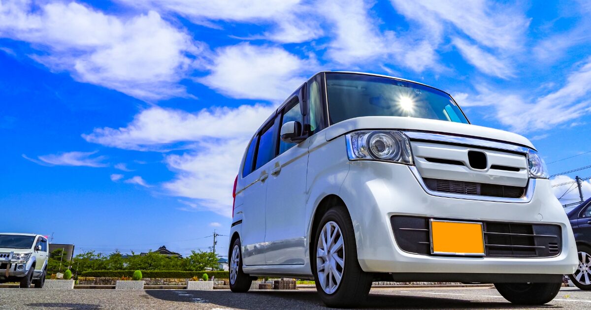 青空の下の駐車場に停められた軽ワゴン車