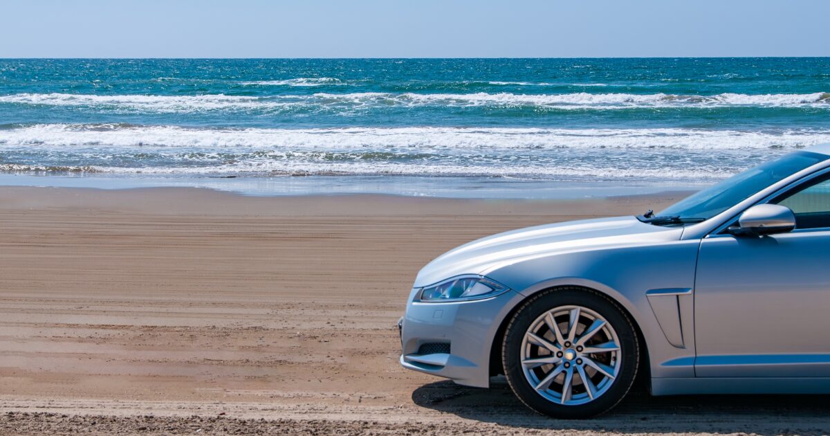 海辺に停車したシルバーのスポーツセダン